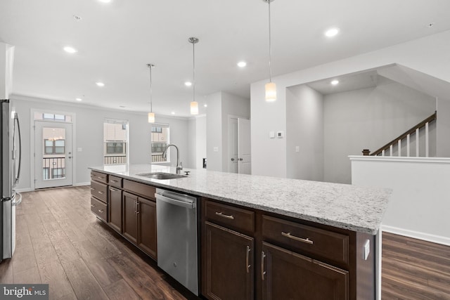 kitchen with decorative light fixtures, stainless steel appliances, a center island with sink, and sink