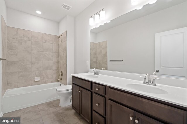 full bathroom featuring tile patterned flooring, tiled shower / bath combo, toilet, and vanity