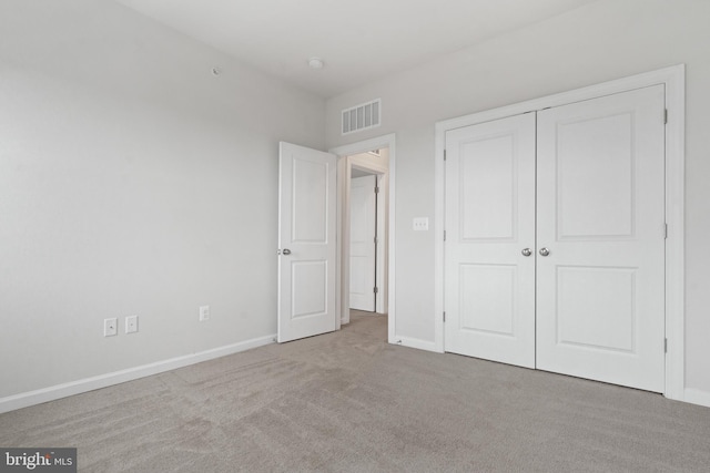 unfurnished bedroom with light carpet and a closet