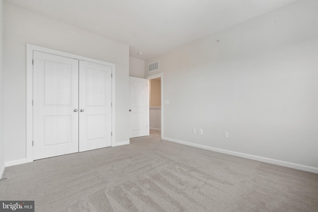 unfurnished bedroom featuring light colored carpet and a closet