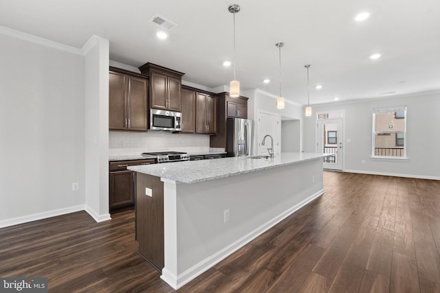 kitchen with a center island with sink, decorative light fixtures, dark brown cabinets, and appliances with stainless steel finishes