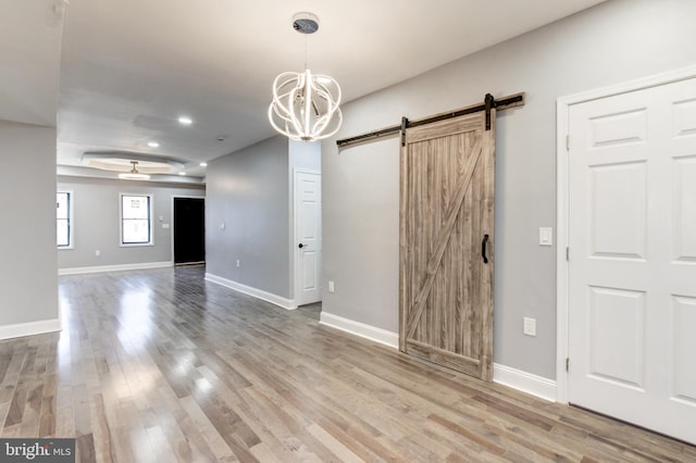 interior space with a barn door, baseboards, and wood finished floors