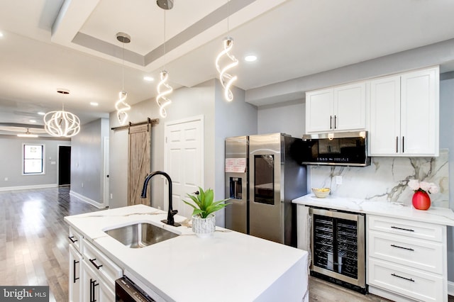 kitchen with backsplash, wine cooler, a barn door, stainless steel fridge, and a sink