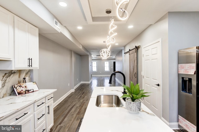 kitchen featuring a sink, a barn door, stainless steel fridge, and dark wood finished floors