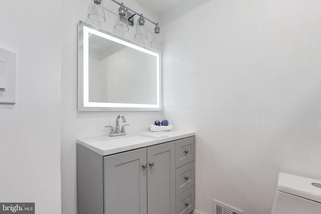 bathroom featuring visible vents, toilet, and vanity