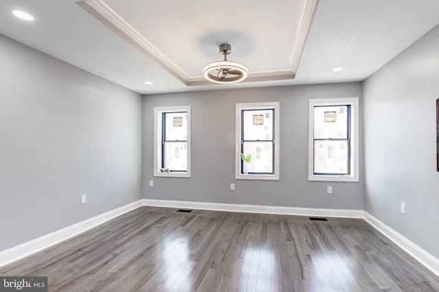 spare room with dark wood-style floors, recessed lighting, a raised ceiling, and baseboards