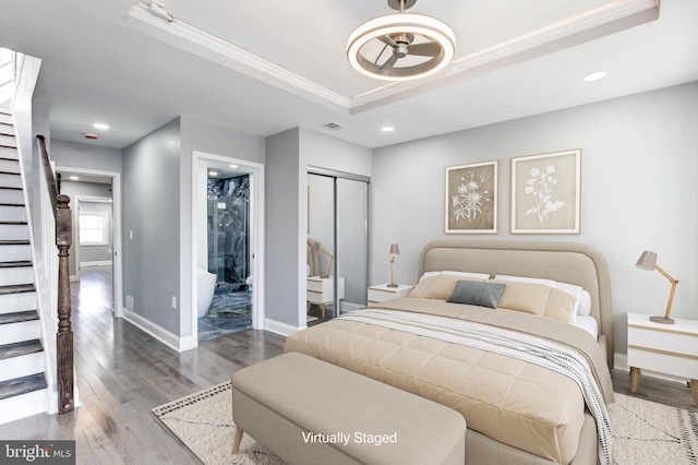 bedroom with visible vents, crown molding, baseboards, a tray ceiling, and wood finished floors