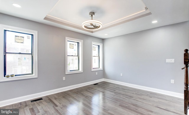 empty room featuring visible vents, baseboards, recessed lighting, wood finished floors, and a raised ceiling