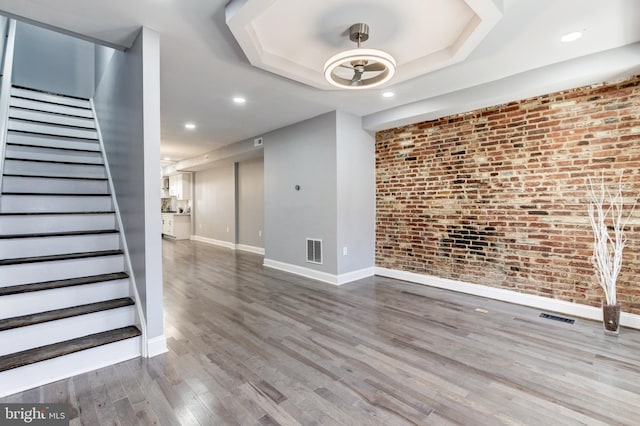 interior space featuring visible vents, brick wall, baseboards, stairway, and wood finished floors