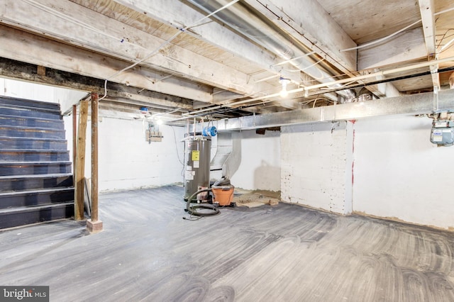 unfinished basement featuring stairway and electric water heater