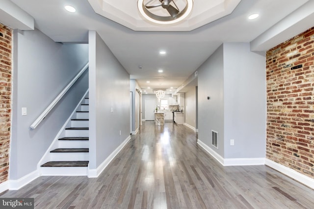 hallway with brick wall, baseboards, and wood finished floors