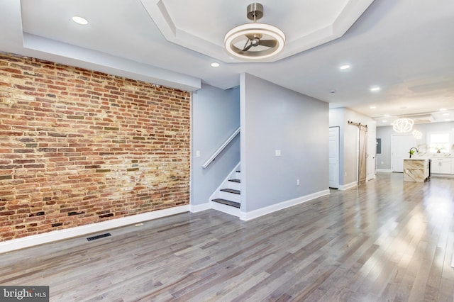 interior space with visible vents, brick wall, a raised ceiling, and a barn door