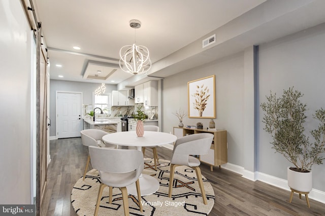 dining room with a notable chandelier, visible vents, a barn door, and dark wood-style flooring