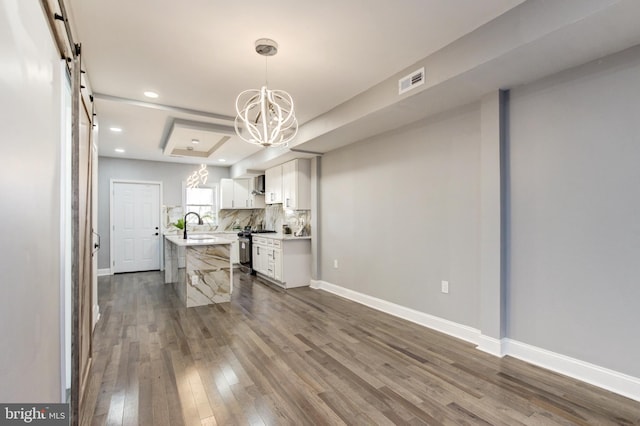 kitchen featuring visible vents, dark wood-type flooring, a barn door, an inviting chandelier, and light countertops