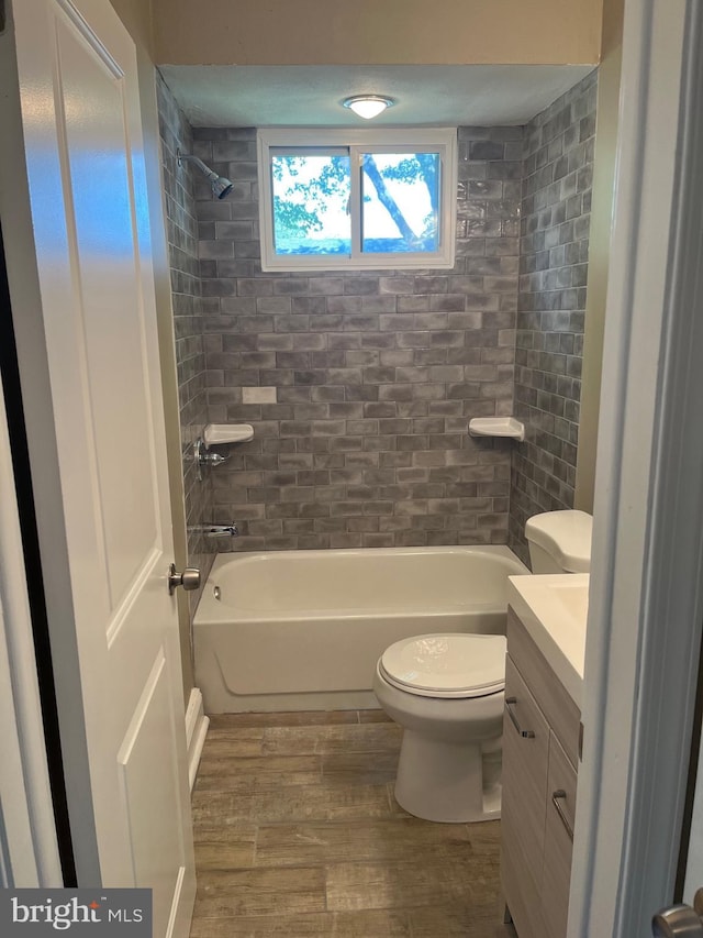 full bathroom with hardwood / wood-style floors, vanity, toilet, and tiled shower / bath combo