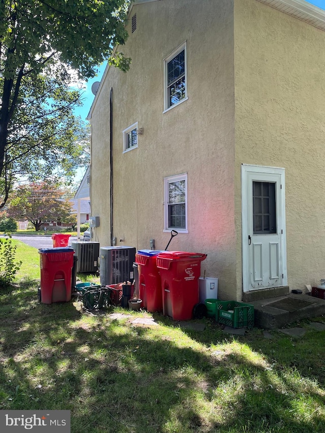 back of house featuring central air condition unit and a lawn