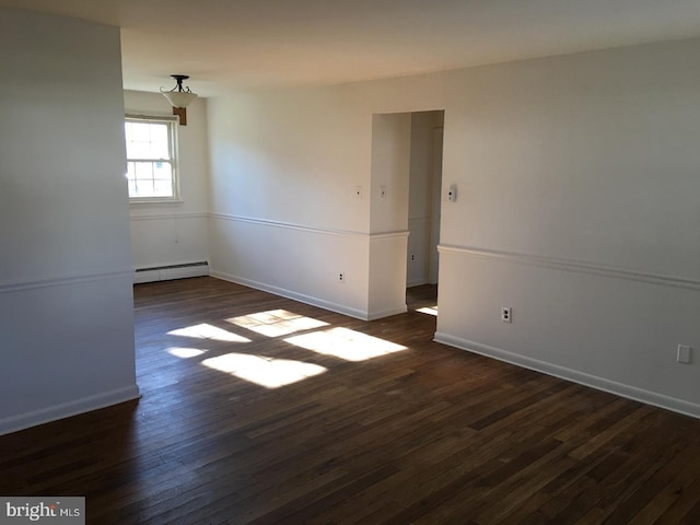 spare room with dark hardwood / wood-style flooring and a baseboard heating unit