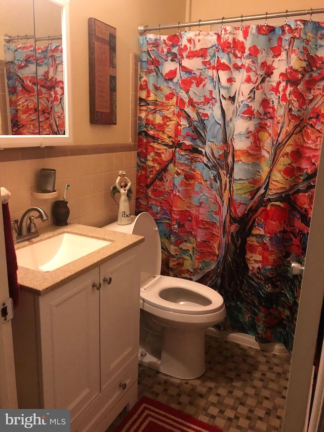 bathroom featuring tile patterned floors, vanity, toilet, and tile walls