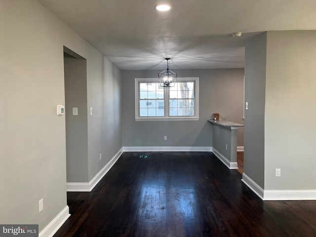 unfurnished dining area with dark hardwood / wood-style floors and an inviting chandelier