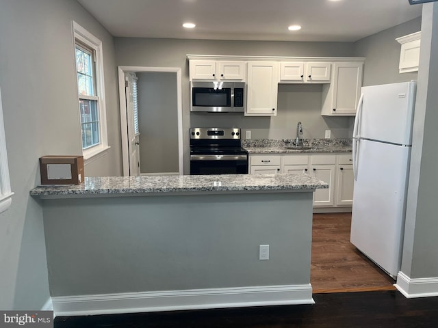 kitchen with white cabinetry, sink, light stone countertops, dark wood-type flooring, and appliances with stainless steel finishes