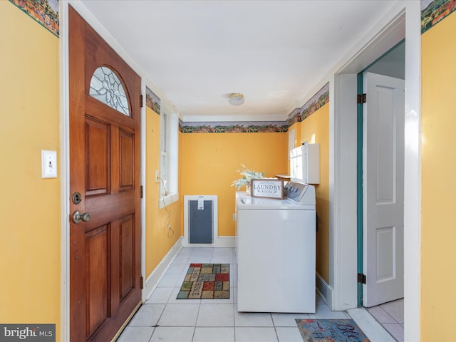 clothes washing area with washing machine and clothes dryer, light tile patterned floors, and cabinets