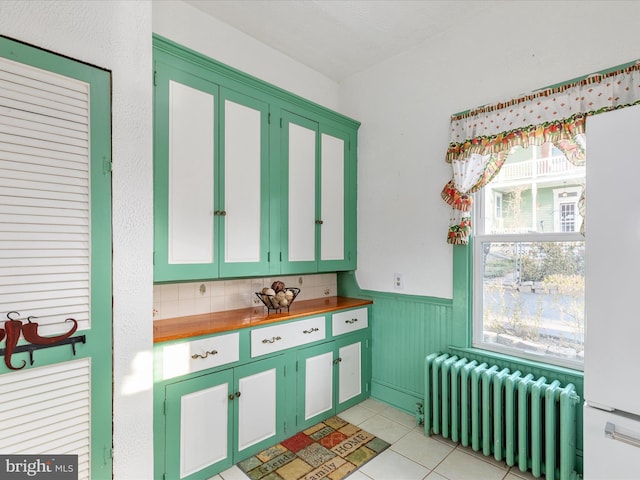 kitchen with butcher block counters, light tile patterned flooring, and radiator heating unit