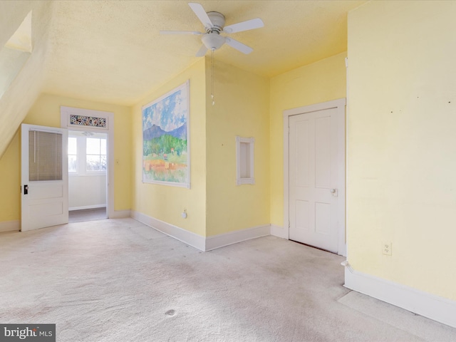 empty room with light carpet, a textured ceiling, ceiling fan, and lofted ceiling