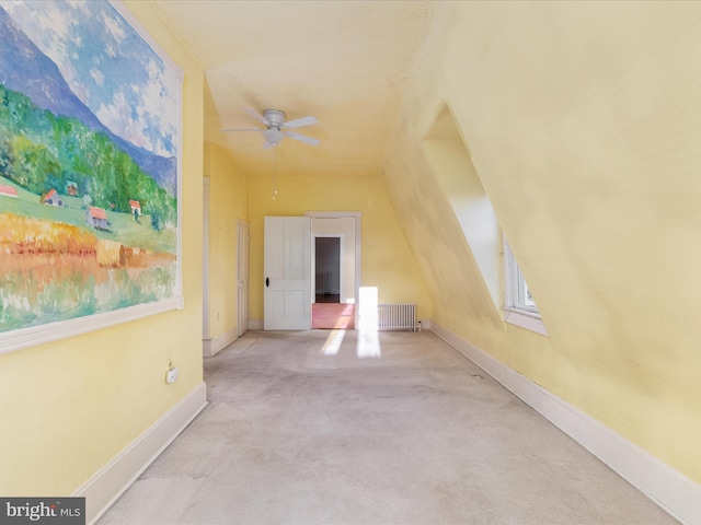 additional living space with radiator, ceiling fan, and light colored carpet