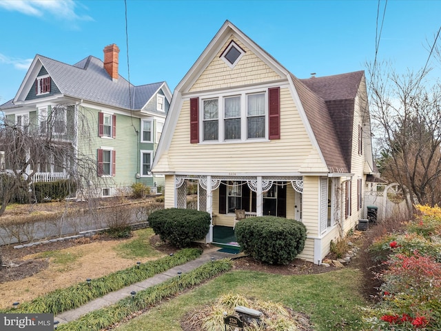 view of front of home with a porch, central AC, and a front lawn