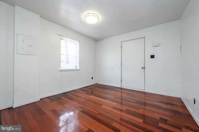 spare room with electric panel and dark wood-type flooring