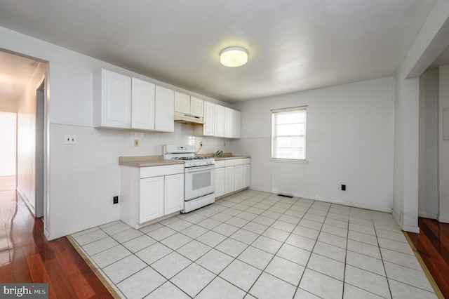 kitchen featuring sink, white cabinets, white range with gas stovetop, and light tile patterned floors