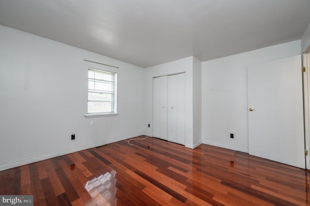 unfurnished bedroom with dark hardwood / wood-style floors and a closet