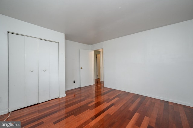 unfurnished bedroom featuring a closet and dark wood-type flooring