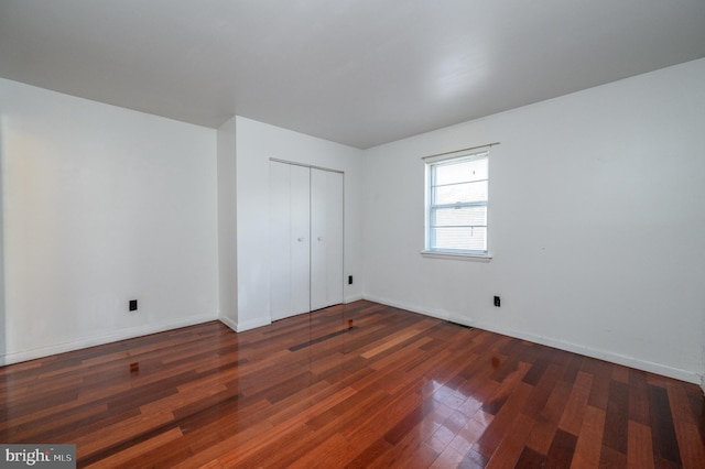 unfurnished bedroom featuring a closet and dark hardwood / wood-style floors