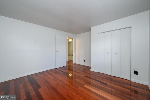 unfurnished bedroom featuring dark hardwood / wood-style flooring and a closet