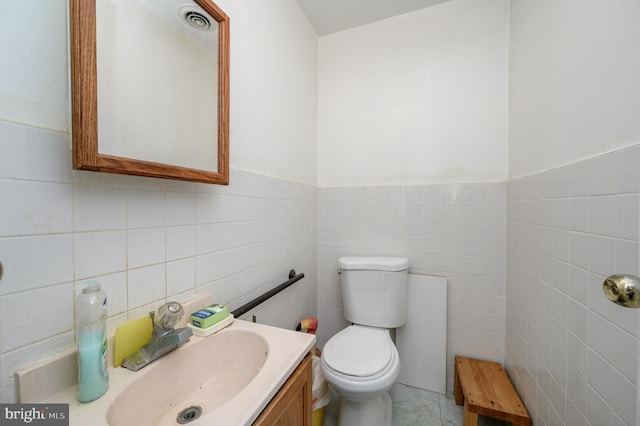 bathroom with vanity, toilet, and tile walls