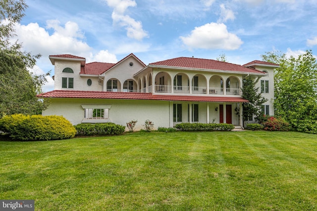 mediterranean / spanish-style house featuring a front yard and a balcony