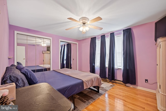 bedroom with two closets, light hardwood / wood-style floors, and ceiling fan