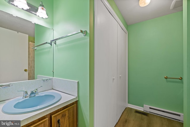 bathroom featuring hardwood / wood-style flooring, vanity, and a baseboard heating unit