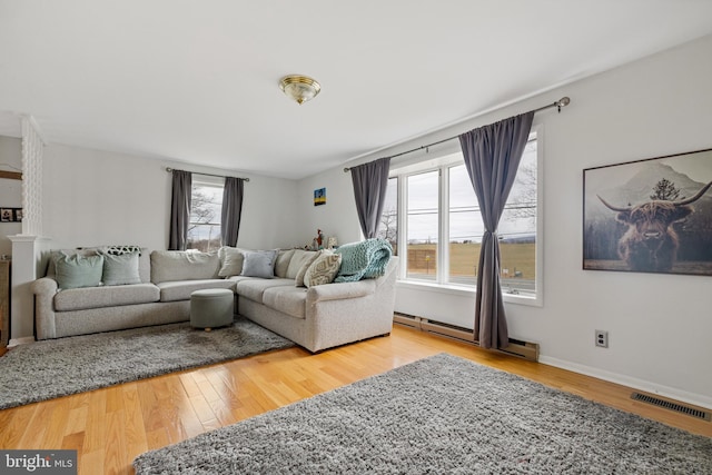 living room featuring a baseboard radiator, wood-type flooring, and a wealth of natural light