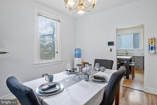 dining space featuring light hardwood / wood-style floors, sink, and a chandelier