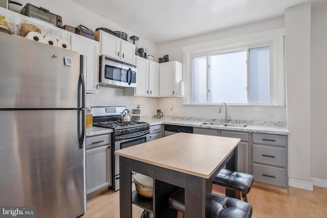 kitchen featuring appliances with stainless steel finishes, light hardwood / wood-style floors, gray cabinetry, and sink