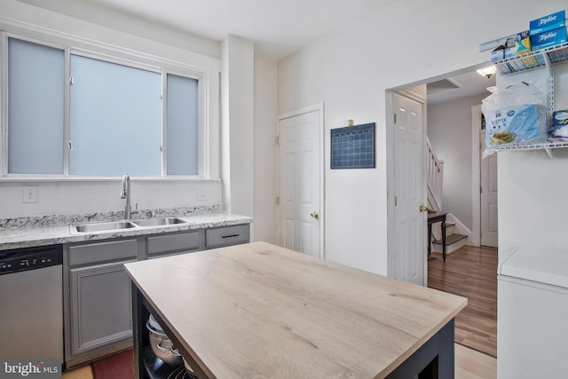 kitchen with gray cabinetry, sink, stainless steel dishwasher, and hardwood / wood-style flooring