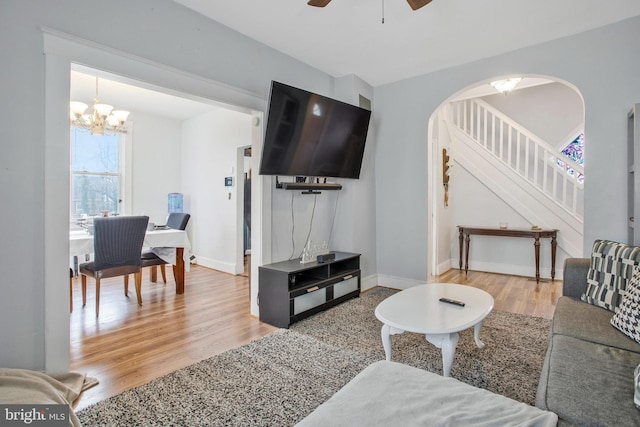 living room with ceiling fan with notable chandelier and light hardwood / wood-style floors