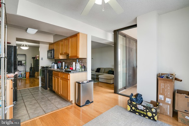 kitchen featuring backsplash, sink, ceiling fan, light wood-type flooring, and a textured ceiling