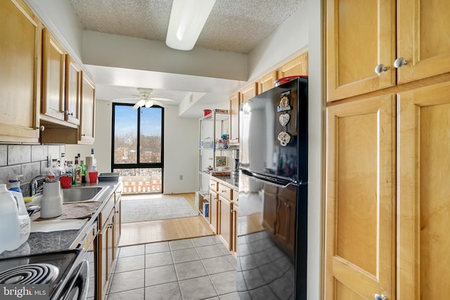 kitchen featuring black refrigerator, backsplash, a textured ceiling, ceiling fan, and light tile patterned flooring