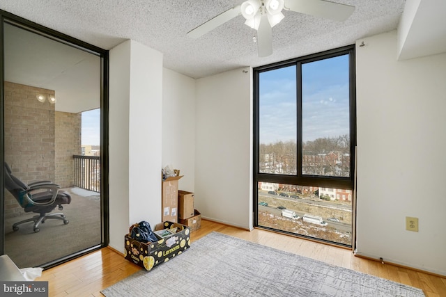 bedroom with a textured ceiling, light wood-type flooring, expansive windows, and ceiling fan