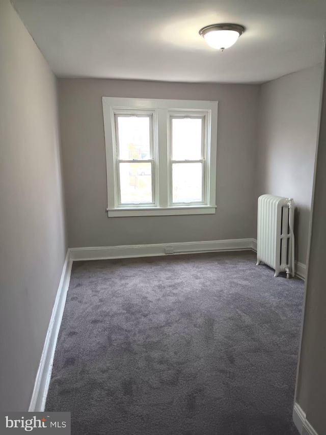 carpeted empty room featuring radiator heating unit