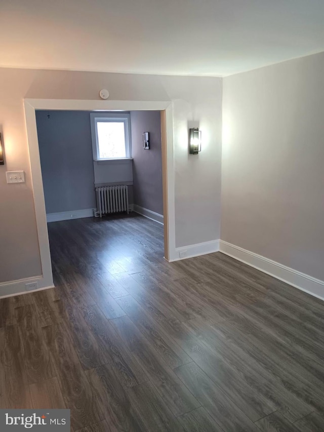 unfurnished room featuring radiator and dark hardwood / wood-style floors