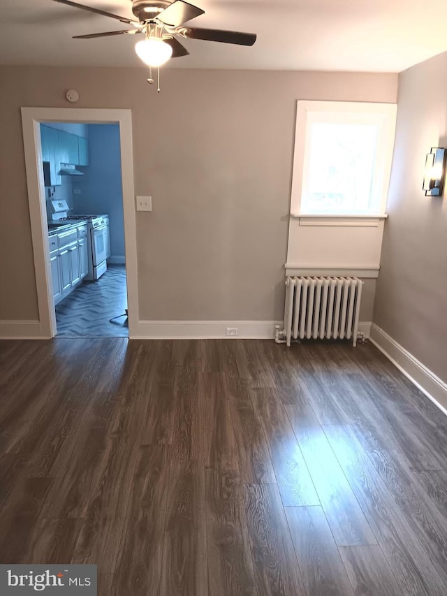 empty room featuring radiator heating unit, ceiling fan, and dark hardwood / wood-style floors